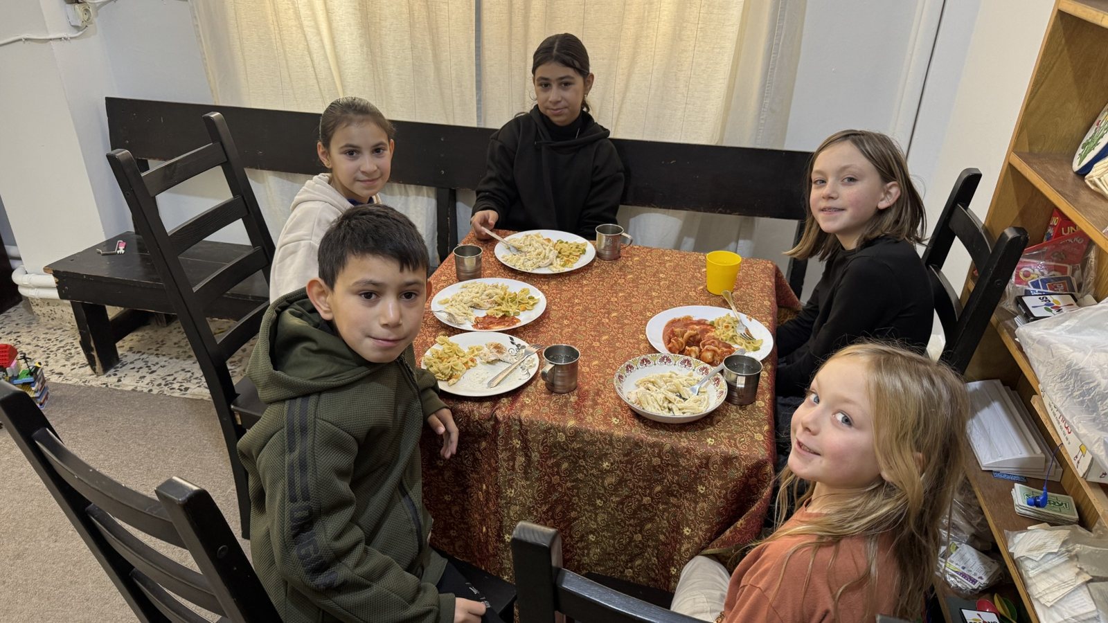 Children sharing a meal together around a table in Jordan